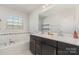 Bright bathroom with a double sink vanity, large mirror, and separate bathtub at 3718 Speer Blvd, Charlotte, NC 28217