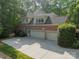 Spacious three car garage with a brick exterior and well maintained driveway with lush green bushes and mature trees at 4646 Eagle Pointe Ct, Denver, NC 28037