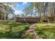 A view of the brick house exterior from the spacious, grassy backyard with mature trees at 518 W Westview St, Gastonia, NC 28052