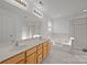 Bathroom showcasing double sinks, soaking tub, and glass enclosed shower with white tile and natural wood vanity at 7262 April Mist Trl, Huntersville, NC 28078