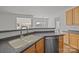 Kitchen sink area with dark countertops, stainless steel dishwasher, and hardwood cabinets at 7262 April Mist Trl, Huntersville, NC 28078