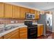 Well-equipped kitchen features wood cabinets, tiled backsplash, stainless steel refrigerator, and black oven at 11929 Kings Castle Ct, Charlotte, NC 28277
