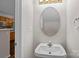 Well-lit powder room featuring an oval mirror, pedestal sink, and view of the kitchen with wood cabinets at 11929 Kings Castle Ct, Charlotte, NC 28277