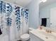 Cozy bathroom featuring a white vanity, toilet, and blue and white leaf-patterned shower curtain at 14923 Colonial Park Dr, Huntersville, NC 28078