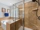 A bathroom featuring a tiled walk-in shower, tiled surround soaking tub, and decorative glass-block window for natural light at 14923 Colonial Park Dr, Huntersville, NC 28078