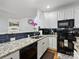 Modern kitchen with granite countertops, black appliances, white cabinets, and a subway tile backsplash at 14923 Colonial Park Dr, Huntersville, NC 28078