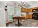 Eat-in kitchen with wooden cabinets and an adjacent dining table in front of a large window at 1509 Burning Lantern Ln, Kannapolis, NC 28081