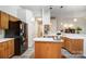 Modern kitchen with wood cabinets, island, black appliances and adjacent entryway at 1509 Burning Lantern Ln, Kannapolis, NC 28081