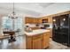 Bright kitchen features wooden cabinets, black appliances, and an island with countertop seating, plus dining table near window at 1509 Burning Lantern Ln, Kannapolis, NC 28081