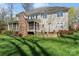 Rear view showcasing the screened-in porch, stone chimney, and landscaped backyard of this well-maintained home at 16123 Chiltern Ln, Huntersville, NC 28078