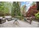Wooden deck featuring wicker furniture, a glass coffee table, and a view of the wooded backyard at 2120 Malvern Rd, Charlotte, NC 28207