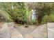 Stone patio featuring an outdoor fire pit and stone benches, surrounded by lush greenery at 2120 Malvern Rd, Charlotte, NC 28207