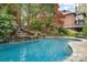 Backyard pool surrounded by lush landscaping and a stone waterfall feature next to brick home at 2120 Malvern Rd, Charlotte, NC 28207