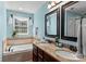 Elegant bathroom features a double sink vanity with granite countertop and a soaking tub under a window at 270 Almora Loop, Mooresville, NC 28115