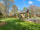 Well-manicured backyard with green lawn, mature trees, and black fencing at 3600 Castellaine Dr, Charlotte, NC 28226