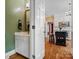View of a powder room connected to a bright kitchen with hardwood floors and white cabinets in the background at 3600 Castellaine Dr, Charlotte, NC 28226
