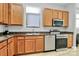 This kitchen features wooden cabinets, stainless steel appliances, and granite countertops, complemented by light wood flooring at 474 New Bern Station Ct, Charlotte, NC 28209