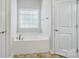 A relaxing soaking tub with a window and tile flooring at 5032 Eagles Crest Ln, Gastonia, NC 28056