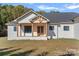 Inviting covered front porch with wood columns and double doors on a white brick home at 5039 Eliza Long Wilkie Dr, Huntersville, NC 28078