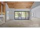 A spacious, unfinished room featuring a wooden ceiling, an exterior door, and a view of an adjacent fireplace at 5039 Eliza Long Wilkie Dr, Huntersville, NC 28078