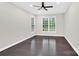 A bright, empty room with a ceiling fan and windows illuminating the hardwood floors at 6520 White Pine Ln, Charlotte, NC 28262