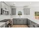 Bright kitchen with modern gray cabinets, white backsplash, stainless steel appliances, and a window view at 701 Applewood St, Kannapolis, NC 28081