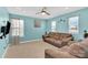 Inviting bonus room with a brown couch, three bright windows and a ceiling fan at 7278 Waterwheel St, Concord, NC 28025