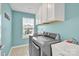 Well-lit laundry room with modern washer and dryer, overhead cabinets, a utility sink and window at 7278 Waterwheel St, Concord, NC 28025