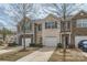 View of townhome row featuring neutral siding, stone accents, attached garages, and tidy landscaping at 9035 Bradstreet Commons Way, Charlotte, NC 28215
