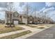 A row of townhomes featuring neutral siding, stone accents, attached garages, driveways, and street view at 9035 Bradstreet Commons Way, Charlotte, NC 28215