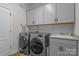 Well-equipped laundry room with modern washer and dryer, storage cabinets, and utility sink at 12709 Messenger Row, Huntersville, NC 28078