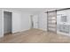 Bedroom with wood floors and decorative wood and glass barn door leading to bathroom at 1315 Vickie Ln, Matthews, NC 28104