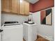 Bright laundry room featuring modern washer and dryer, wooden cabinetry, and decorative wall art at 2018 Puddle Pond Rd, Indian Trail, NC 28079