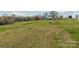 Expansive land showcasing its natural beauty with lush greenery, scattered trees, and a charming house in the background at 3526 Harmony Hwy, Harmony, NC 28634