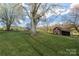 Charming red barn with attached lean-to nestled on a lush green lawn under a bright sky at 3526 Harmony Hwy, Harmony, NC 28634