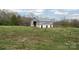 Old barn on a grassy hill with trees behind the barn at 3526 Harmony Hwy, Harmony, NC 28634