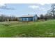 Blue barn on a grassy hill with lush trees surrounding the property at 3526 Harmony Hwy, Harmony, NC 28634