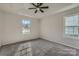 A sunlit bedroom features neutral walls, carpet flooring, and a view of the outdoors from two windows at 3753 Capps Hill Dr, Charlotte, NC 28216