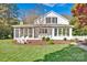 Charming white home with a screened-in porch, surrounded by lush greenery and a manicured lawn at 411 Walnut St, Davidson, NC 28036