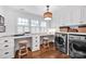 Bright laundry room featuring white cabinetry, workspace, laundry machines, and wood floors at 411 Walnut St, Davidson, NC 28036
