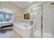 Bright bathroom featuring a soaking tub, glass shower, and access to the main bedroom at 45008 Wigeon Ln # 101, Indian Land, SC 29707