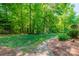 Secluded backyard features a stone path, lush grass, and mature trees at 5232 Silchester Ln, Charlotte, NC 28215