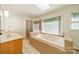 Bathroom with jacuzzi tub, glass shower, window, and vanity with sink at 5232 Silchester Ln, Charlotte, NC 28215