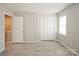 A bedroom features gray tone laminate flooring, light gray walls, a closet with louvered doors, and a window at 1113 Keswick Pl # 118, Monroe, NC 28112