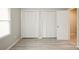 A bedroom with gray tone laminate flooring features a white closet with louvered doors at 1113 Keswick Pl # 118, Monroe, NC 28112