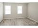 A bedroom features gray tone laminate flooring, light gray walls, two windows, and a white closet with louvered doors at 1113 Keswick Pl # 118, Monroe, NC 28112