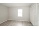 A bedroom with light grey walls, gray tone laminate flooring, and a white closet with louvered doors at 1113 Keswick Pl # 118, Monroe, NC 28112