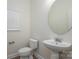 Well-lit powder room features a toilet, sink with an oval mirror, and a window with horizontal blinds at 125 Colville Rd, Mooresville, NC 28117