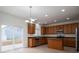 Well-lit kitchen boasts stainless steel appliances, wood cabinets, and a sliding glass door to the backyard at 125 Colville Rd, Mooresville, NC 28117