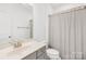 This stylish bathroom features a gray vanity with a sink, toilet, and shower with a neutral-colored shower curtain at 12706 Heath Grove Dr, Huntersville, NC 28078